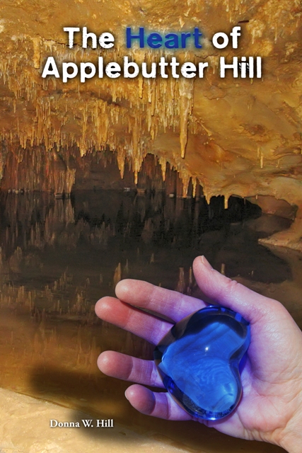 Book cover for The Heart of Applebutter Hill by Donna W. Hill shows a cave scene - stalactites reflected in an underground lake, while a hand holds the Heartstone of Arden-Goth: photos, Rich Hill;, design, Lizza Studios.