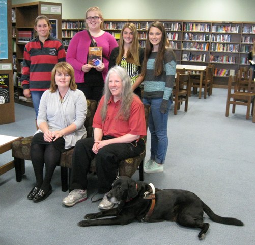 lackawanna trail high library (Factoryville, PA): Donna W. Hill on sofa w librarian kelly hopkins; 4 students (l-r: Taylor Selwood,Jordan Flynn, Ally Decker and Annika Kongvold ) stand behind. Jordan holds Donna's novel The Heart of Applebutter Hill & Donna's black Lab guide dog, Hunter, watches from the floor: photo by rich hill.