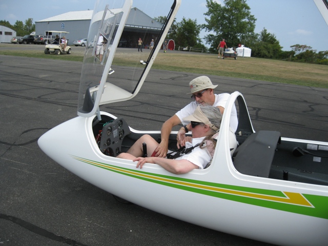 Pre-Flight Instruction at National Soaring Museum in NY: Donna sits in front seat of High-Performance Glider; pilot standing by plane on runway - photo by Rich Hill.